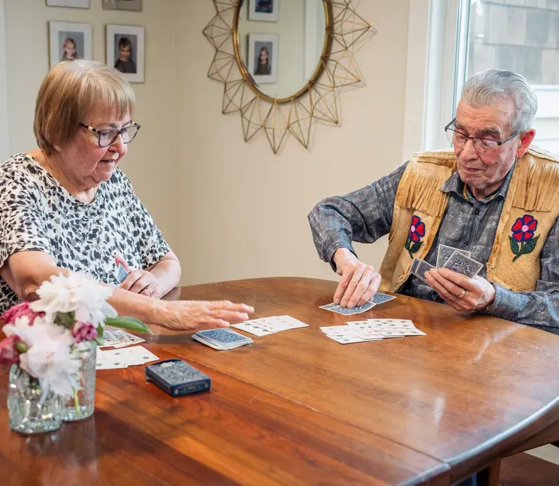 Casal de idosos joga cartas na mesa da sala de jantar